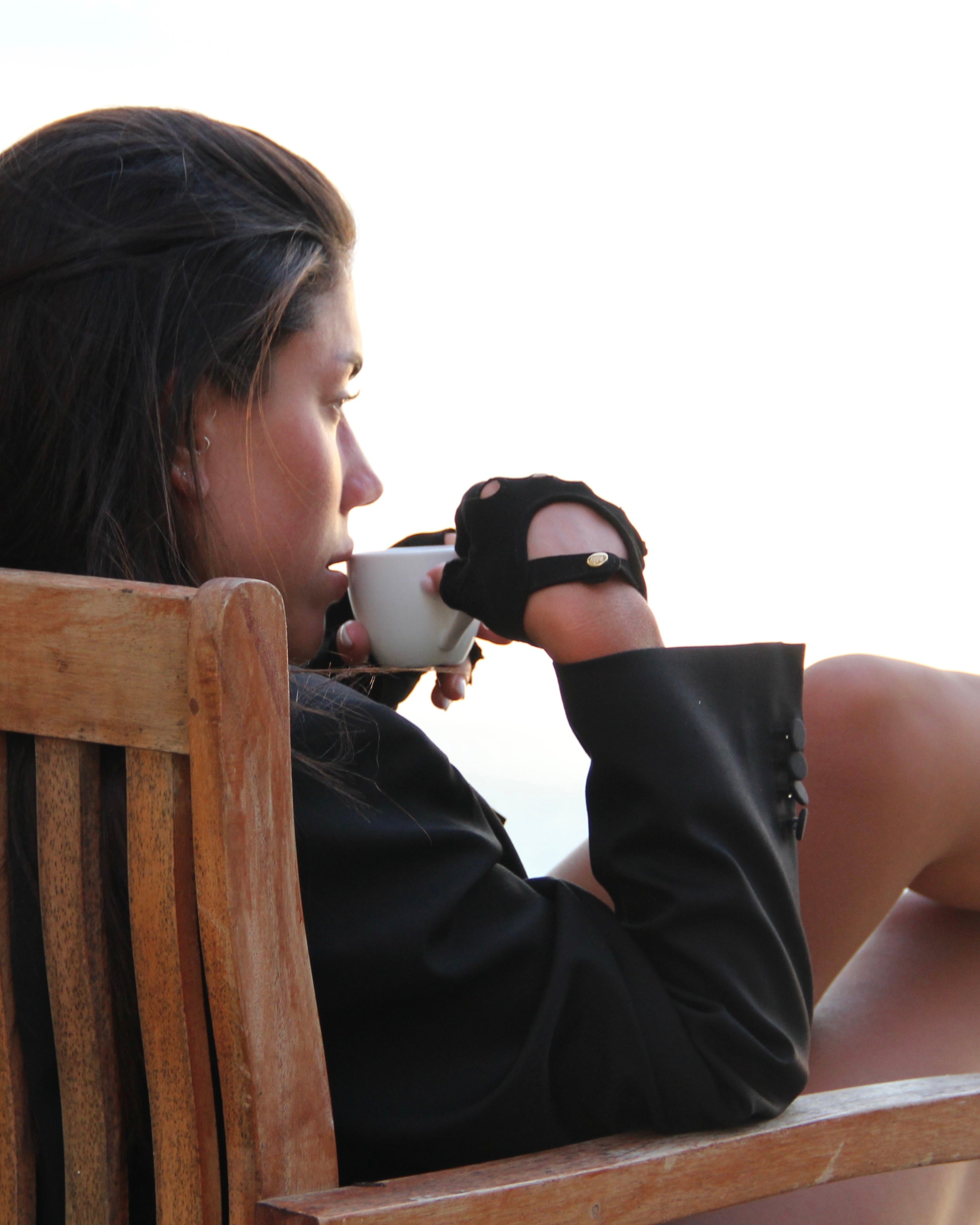 Black leather gloves worn with a coffee cup on a deck chair by