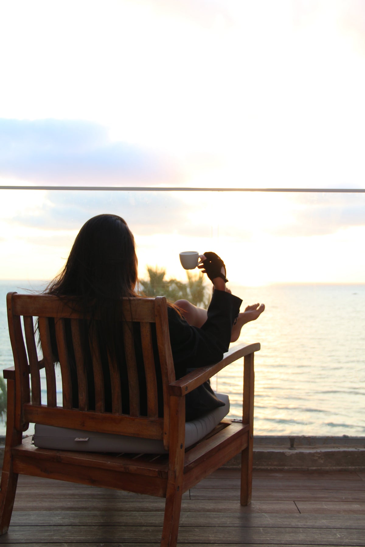 Black suede fingerless gloves worn on a deck chair overlooking the water at dusk