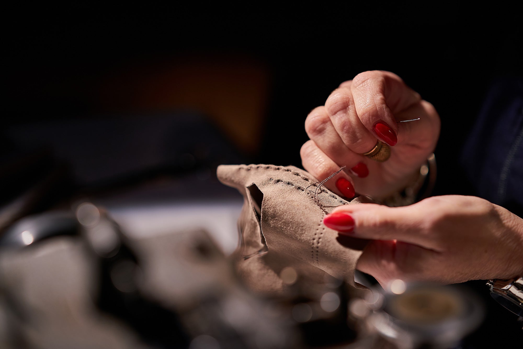 A close-up of a skilled artisan's hand sewing a leather glove with precision, highlighting the craftsmanship behind every stitch.