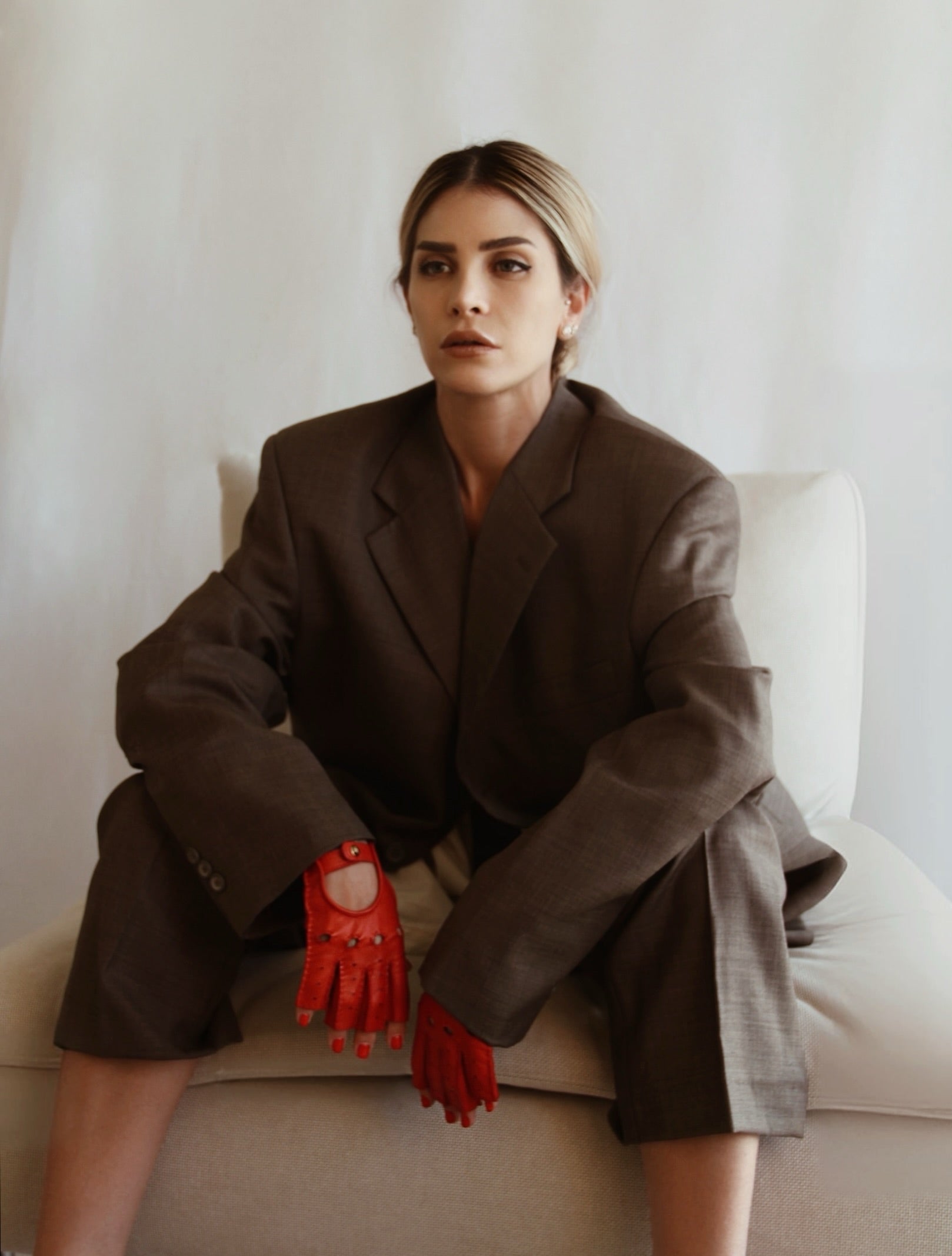 A woman dressed in a suit, and red fingerless leather gloves- liv.