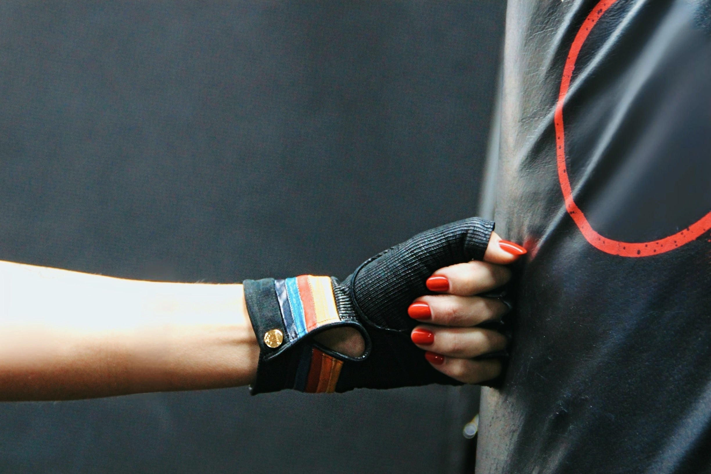 Roxy 79 black short fingerless leather gloves with striped cuff gripping a boxing pad