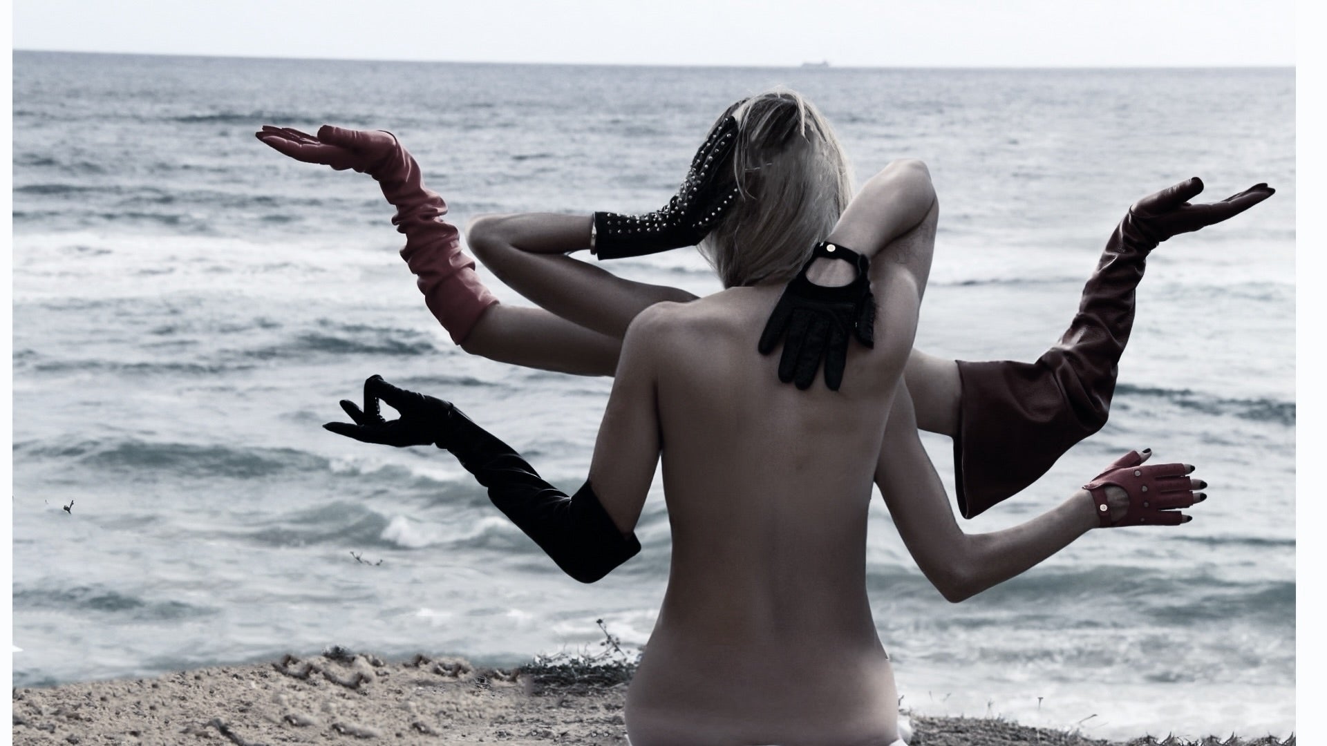 Multiple arms in black leather gloves outstretched against the sea