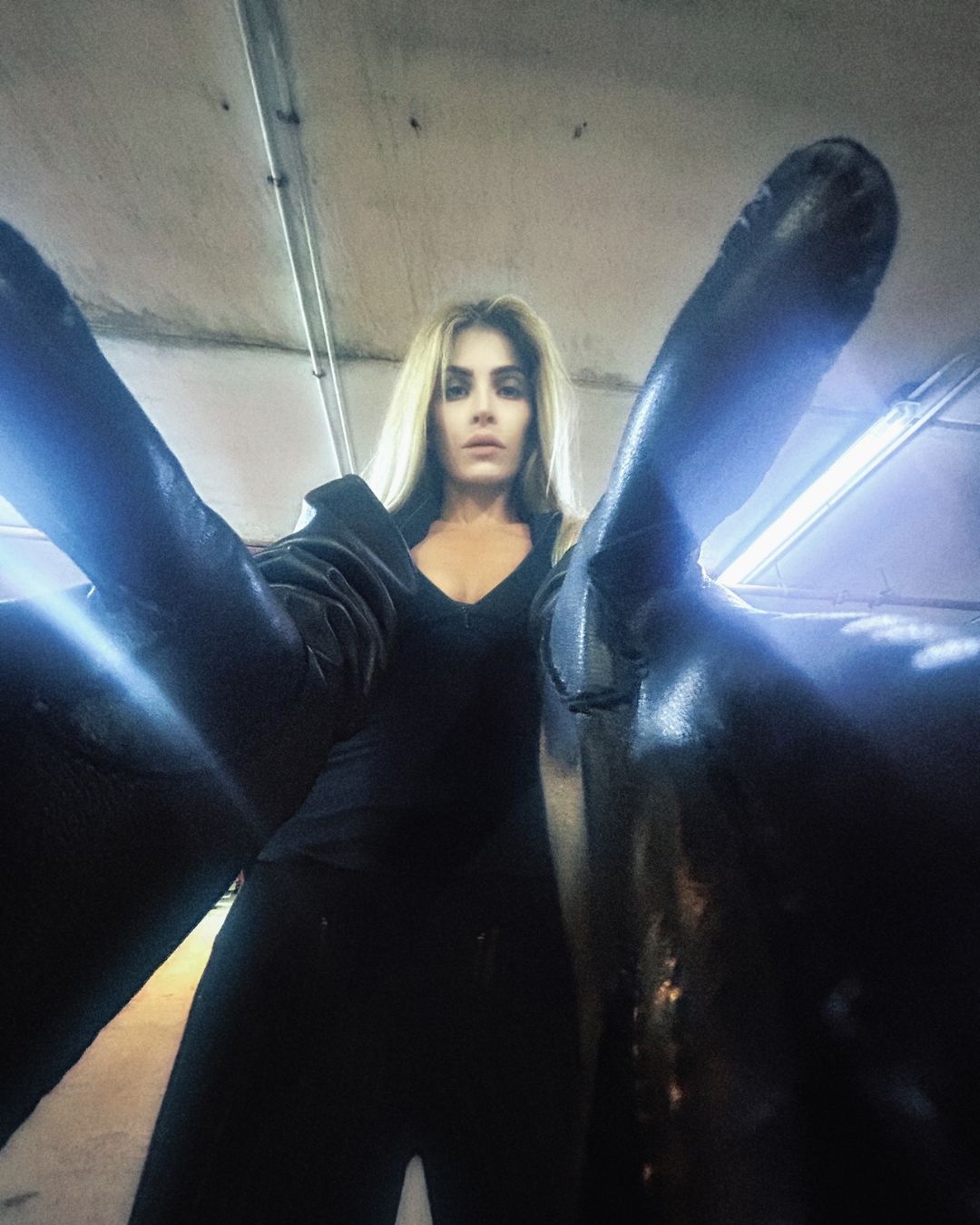 Nikita long oversized black leather gloves worn with arms outstretched